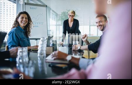 Geschäftsleute, die im Sitzungssaal des Büros sitzen und während einer Besprechung lächeln. Gruppe von Geschäftsleuten, die während einer Präsentation lächeln. Stockfoto