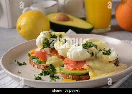 Eier Benedikt mit geräuchertem Lachs, Avocado-Scheiben und Sauce Hollandaise Stockfoto