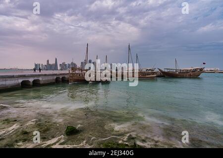 Skyline von Doha von der corniche Promenade am Nachmittag Weitwinkelaufnahme Zeigt Daus mit Qatar-Flagge im arabischen Golf in Vordergrund Stockfoto