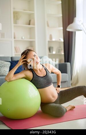 Schwangere Frau trainieren auf Fitball zu Hause. Schwangerschaft, Sport, Fitness, Menschen und gesunde Lebensweise Konzept Stockfoto