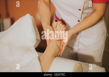 Eine junge Frau, die in einem Schönheitssalon Füße massiert Stockfoto