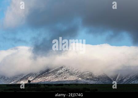 Atemberaubende Landschaft Bild von Skiddaw schneebedeckten Bergkette in Lake District im Winter mit niedrigen Wolken um Gipfel Stockfoto