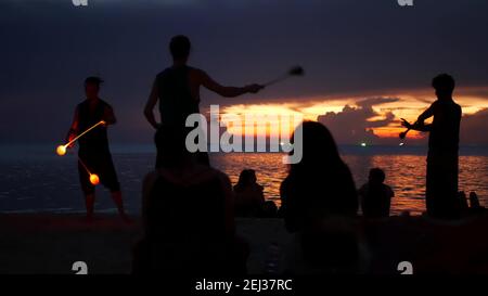 PHANGAN, THAILAND - 23. MÄRZ 2019 Zen Beach. Silhouetten von Darstellern am Strand während des Sonnenuntergangs. Silhouetten junger anonymer Entertainer, die Proben Stockfoto