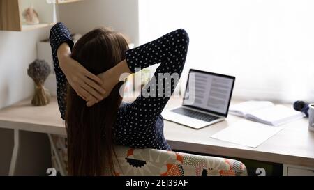 Rückansicht der Frau Entspannen Sie sich im Stuhl am Arbeitsplatz Stockfoto