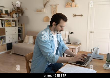 Serious männliche Arbeit online auf Laptop von zu Hause aus Stockfoto