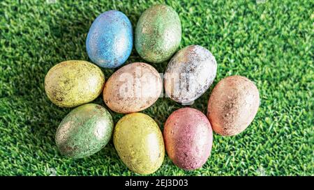 Ostereier in Pastellfarben auf grünem Hintergrund mit Grasstruktur. Blick von oben. Stockfoto