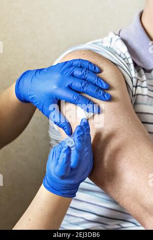 Ein Arzt impft einen Mann gegen Coronavirus in einer Klinik. Nahaufnahme. Das Konzept der Impfung, Immunisierung, Prävention gegen Covid-19 Stockfoto