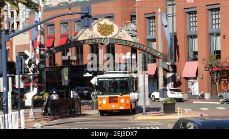 SAN DIEGO, CALIFORNIA USA - 13 FEB 2020: Gaslamp Quarter historisches Eingangsbogenschild auf 5th Avenue. Orange kultige Retro-Trolley, Hop-on-Hop-off-Bus und Stockfoto