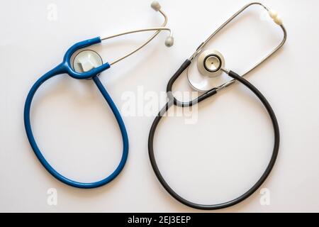 Zwei Stethoskope in abgerundeter Form, eines blau und eines schwarz Mit weißem Hintergrund Stockfoto