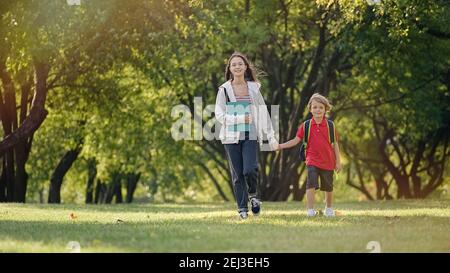 Schule Kinder kommen gut gelaunt von der Schule zurück. Bruder und Schwester laufen den Park entlang Stockfoto