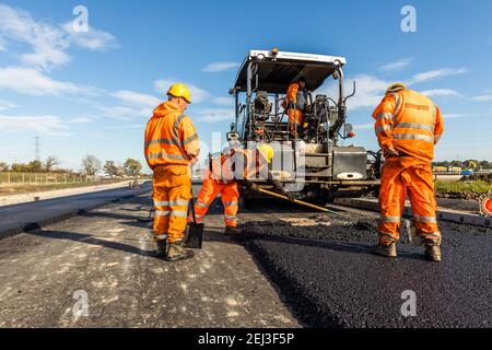 Arbeiter legen frischen Asphalt auf einer neuen Straße Stockfoto