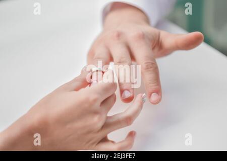 Die Braut legt ihren Ehering auf den Finger ihres Bräutigams. Stockfoto