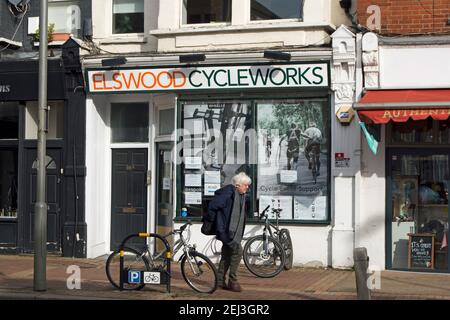 Außenansicht von Elswood Cycleworks, einem Fahrradladen, der Service und Reparaturen in putney, london, england anbietet, mit einem älteren Mann, der vorbeigeht Stockfoto