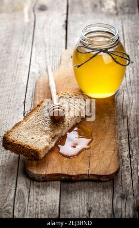 Honig in einem Glas, Scheibe Brot, Weizen und Milch auf einem alten Vintage-Holztisch von oben. Frühstück im ländlichen oder rustikalen Stil. Hintergrund la Stockfoto