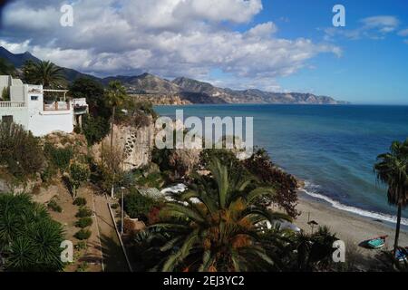 Szenische Aufnahme der Küste von Nerja mit Palmen, Bergen, blauem Himmel und Seeseite Stockfoto