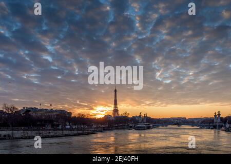 Paris, Frankreich - 12. Februar 2021: Stadtbild von Paris im Winter. Schiffe und Brigde über die seine mit Eiffelturm im Hintergrund und dramatisch bewölkt