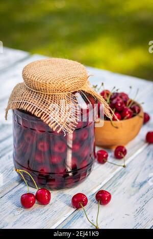 Hausgemachtes Kirschfrucht auf Holztisch im Garten. Kirschen-Konserve im Glas. Selektiver Fokus Stockfoto