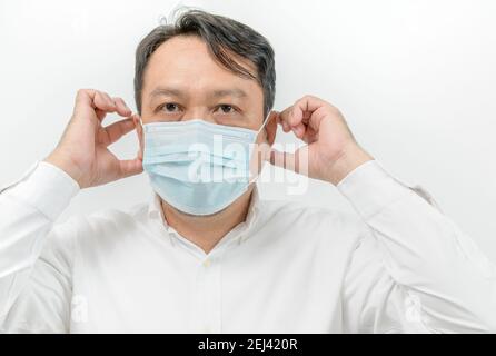 Portrait von asiatischen Mann in weißem Hemd trägt Gesicht medizinische Maske zum Schutz vor Viruserkrankungen isoliert auf weißem Hintergrund, Business und Gesundheit Auto Stockfoto