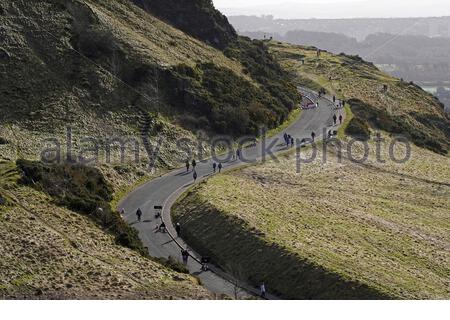 Edinburgh, Schottland, Großbritannien. Februar 2021, 21st. Menschen genießen die Sonne und im Freien im Holyrood Park. Leute, die auf dem Queens Drive laufen. Kredit: Craig Brown/Alamy Live Nachrichten Stockfoto