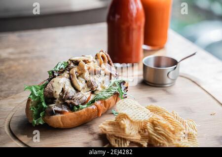 Leckere Hot Dogs mit Käsesauce serviert mit gebratenen Kartoffeln Raster auf dem Tisch Stockfoto