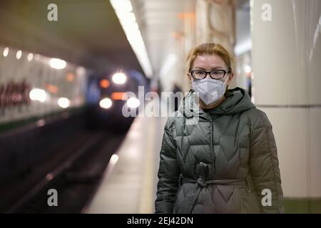 Reife Frau in Atemschutzmaske wartet auf Zug in Plattform der U-Bahn-Station. Konzept der neuen Lebenswirklichkeit während der COVID 19 Pandemie Stockfoto