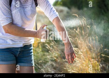 Insektenschutz. Frau, die in der Natur Mückenschutz auf die Hand gibt. Hautschutz gegen Zecken und andere Insekten Stockfoto