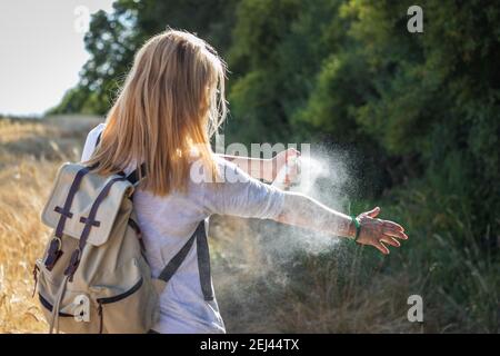 Frau Tourist Anwendung Mückenschutz auf der Hand während der Wanderung in der Natur. Insektenschutz. Hautschutz gegen Zecken und andere Insekten. Stockfoto