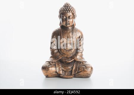 Eine Bronze buddha innen Souvenir-Statue in Lotusposition isoliert auf einem schlichten weißen Hintergrund und Oberfläche. Stockfoto