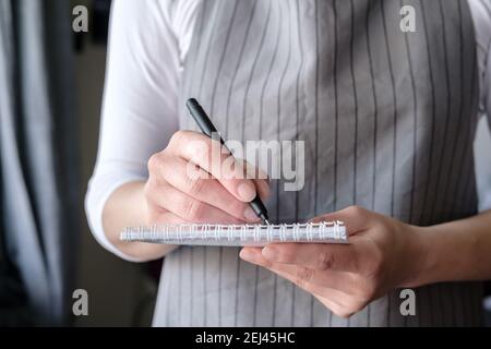 Kellnerin mit Notizbuch und Stift nimmt eine Bestellung vom Kunden an und schreibt sie in einen Notizblock. Gastfreundschaft des Personals. Stockfoto