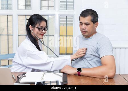 Die Ärztin untersucht im Büro den Herzschlag ihrer älteren Patientin mit Stethoskop. Stockfoto