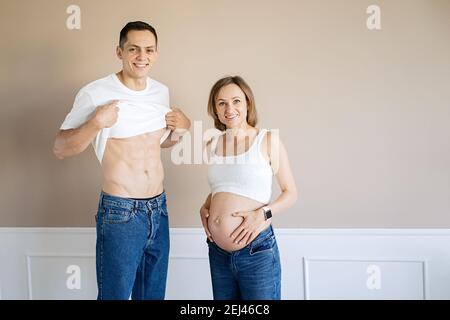 Schwangere Frau und liebevoller Ehemann zeigen sich gegenseitig ihre Bäuche Stockfoto