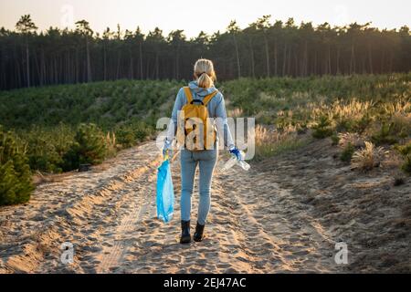 Ehrenamtlich für die Umwelt. Frau hält Plastikmüll und Müllbeutel im Wald. Halten Sie die Natur ohne Plastikverschmutzung! Stockfoto