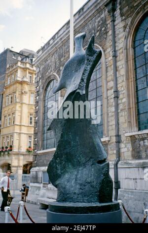 Eine Bronzeskulptur aus dem Jahr 1976, Henry Moores ‘Standing Figure: Knife Edge’, ausgestellt vor der St. Lawrence Jewry Church, Guildhall Yard, City of London, England, UK 1993. Dies war Teil der ‘Art in the City’ von 1993 und zielte darauf ab, Skulpturen zwischen den Grünflächen und der unverwechselbaren Architektur der City of London zu setzen. ‘Standing Figure: Knife Edge’ ist eine Bronzeskulptur von Henry Moore. Es wurde in zwei Versionen gegossen, ‘Standing Figure: Knife Edge’ (1961), und wie hier gezeigt, eine größere ‘Large Standing Figure: Knife Edge’ (1976). Es wurde an vielen Orten weltweit ausgestellt. Stockfoto