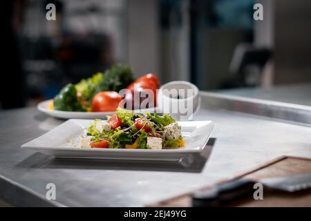 Frischer griechischer Salat mit Tomaten, Salat und Feta in der Restaurantküche Stockfoto