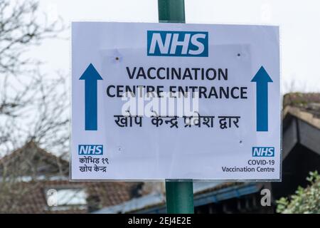 Farnborough, Hampshire, England, Großbritannien. Februar 21st, 2021. Das britische Coronavirus Covid-19-Impfprogramm kommt im Allgemeinen gut voran, aber es gab eine geringere Aufnahme des Impfstoffs bei BAME-Menschen, einschließlich der südasiatischen Gemeinschaft. Abgebildet ist ein zweisprachiges Schild zu einem Impfzentrum in englischer und nepalesischer Sprache in einem Gebiet von Hampshire mit einer großen nepalesischen Gemeinde. Stockfoto