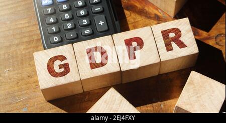 GDPR Wort in Holzwürfel und Rechner auf Holztisch geschrieben. Stockfoto