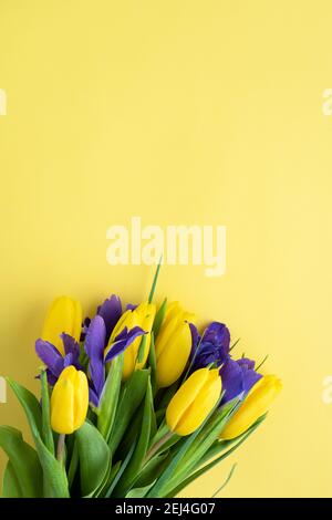 Bouquet von gelben Tulpen und Iris auf gelbem Hintergrund. Draufsicht Stockfoto