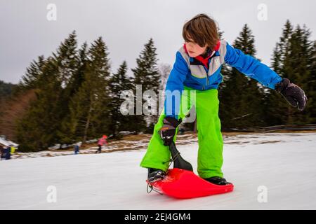 Junge, 9 Jahre alt, Rodeln stehend mit dem Zipfelbob, Hochschwarzeck, Ramsau, Berchtesgadener Land, Oberbayern, Bayern, Deutschland Stockfoto