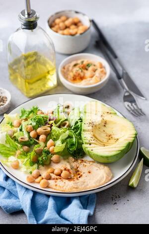 Salatschüssel mit Kichererbsen Hummus, Grüns und Avocado. Gesunder veganer Salat mit Olivenöl Stockfoto