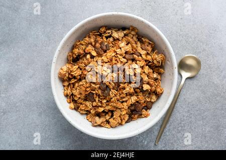 Hausgemachtes Haferrosinengranola in Schale auf grauem Betongrund, Draufsicht. Gesundes Frühstückscerealien Stockfoto