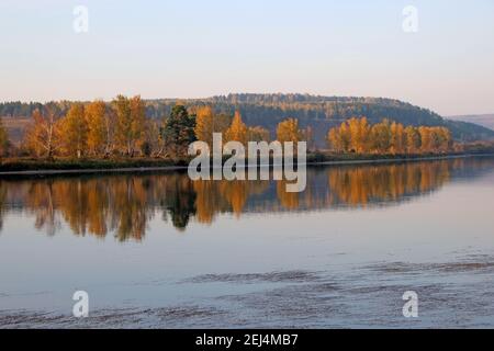 Blick auf die ruhige Flussoberfläche, wo reflektierte Herbstlandschaft wie in einem großen Spiegel. Stockfoto