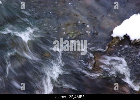 Der Bergfluss fließt über die Felsen sprudelnd und schäumend. Stockfoto