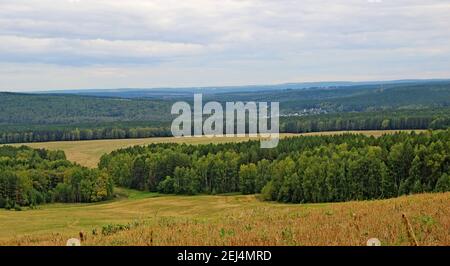 Erstaunliche Herbstlandschaft - Blick von einem Hügel auf eine hügelige Gegend unter einem düsteren Herbsthimmel. Stockfoto