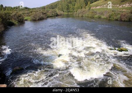 Der Bergfluss fließt über die Felsen sprudelnd und schäumend. Stockfoto