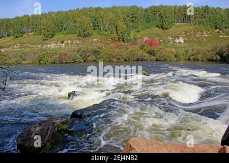 Der Bergfluss fließt über die Felsen sprudelnd und schäumend. Stockfoto