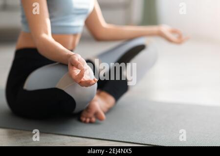 Ein kurzer Schnitt einer Frau in Sportkleidung, die zu Hause meditiert Stockfoto