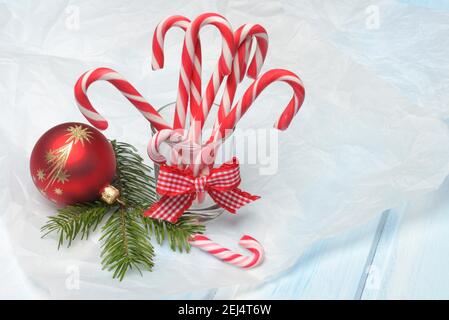 Candy Stöcke in Glas und Weihnachtsbaumkugel mit Tannenzweig, rot-weiß Stockfoto