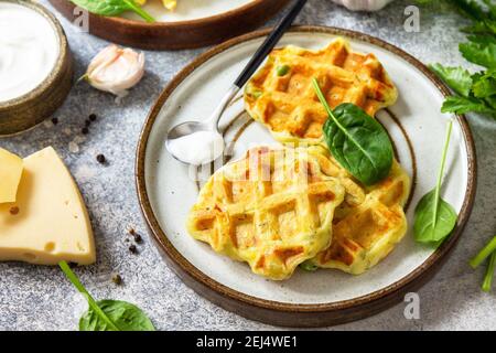 Kartoffelwaffeln mit Erbsen, Paprika, Käse und Kräutern, ein schneller Snack auf einem Teller auf einer grauen Steinplatte. Stockfoto