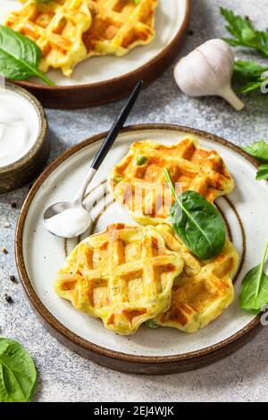 Kartoffelwaffeln mit Erbsen, Paprika, Käse und Kräutern, ein schneller Snack auf einem Teller auf einer grauen Steinplatte. Stockfoto