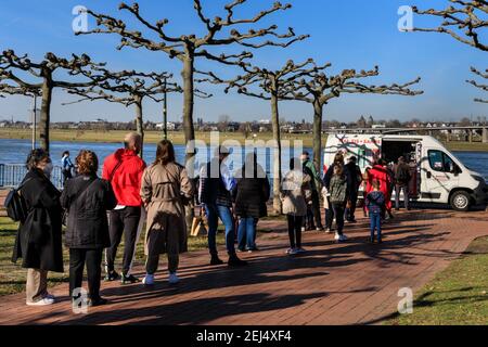 Düsseldorf, NRW, 2021. Vor einem Eiswagen hat sich eine lange Schlange gebildet. Am Sonntagnachmittag genießen die Menschen bei schönem, warmen Sonnenschein mit Temperaturen bis zu 18 Grad im beliebten Medienhafen, einem umbauten Gebiet am Rhein, in dem Medienunternehmen, Büros, Unterhaltung, Restaurants und Freizeiteinrichtungen in Düsseldorf, der Hauptstadt des bevölkerungsreichsten Bundeslandes Nordrhein-Westfalen, angesiedelt sind. Kredit: Imageplotter/Alamy Live Nachrichten Stockfoto